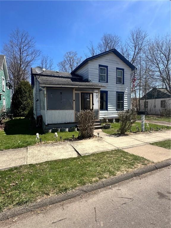 traditional-style home featuring a shingled roof and a front yard
