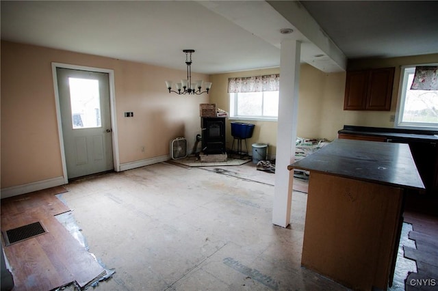 dining area with a wood stove, baseboards, plenty of natural light, and visible vents
