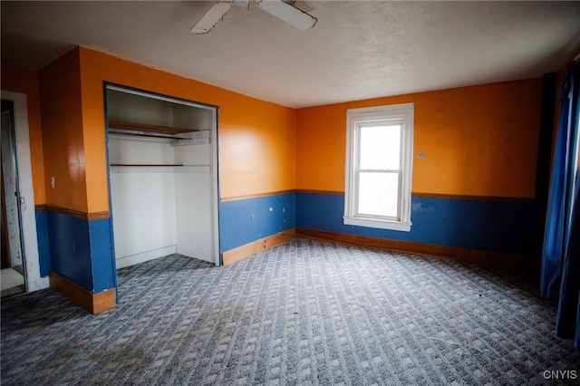 unfurnished bedroom featuring carpet flooring, a closet, baseboards, and a ceiling fan