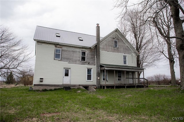 back of property with covered porch, a chimney, and metal roof