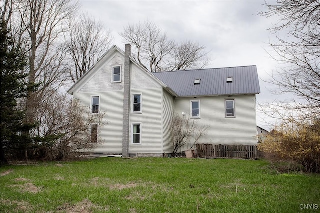 rear view of property featuring metal roof, a yard, and a chimney