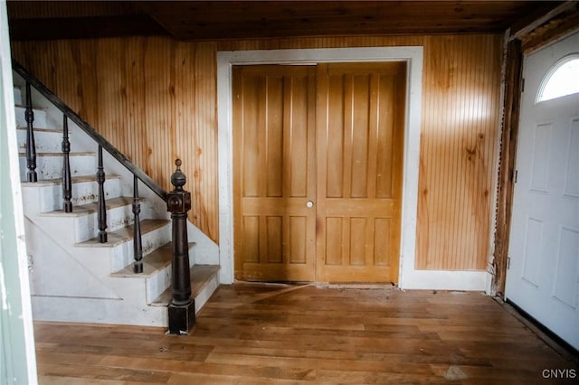 entryway with stairway, wood walls, and wood finished floors