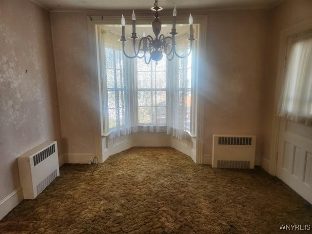 106 Saxton St, Lockport City, NY 14094 - unfurnished dining area with carpet floors, ornamental molding, radiator, and a notable chandelier