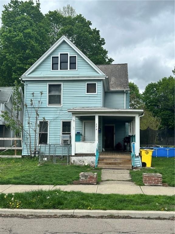 view of front of home featuring a porch, a trampoline, and a front lawn