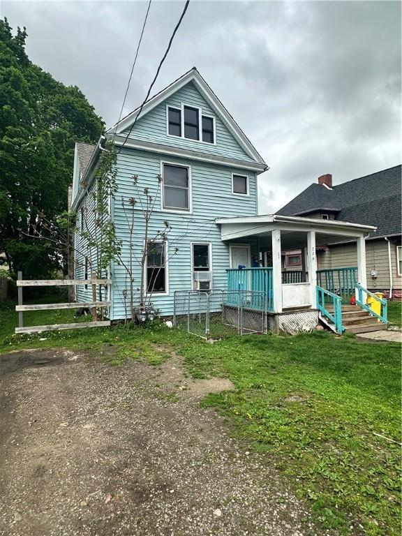 rear view of property featuring a porch and a yard