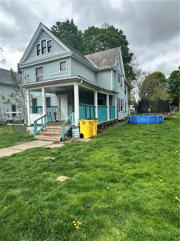 back of property with a trampoline, a yard, and a porch
