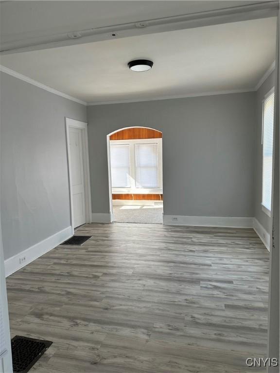 unfurnished room featuring ornamental molding, baseboards, visible vents, and wood finished floors