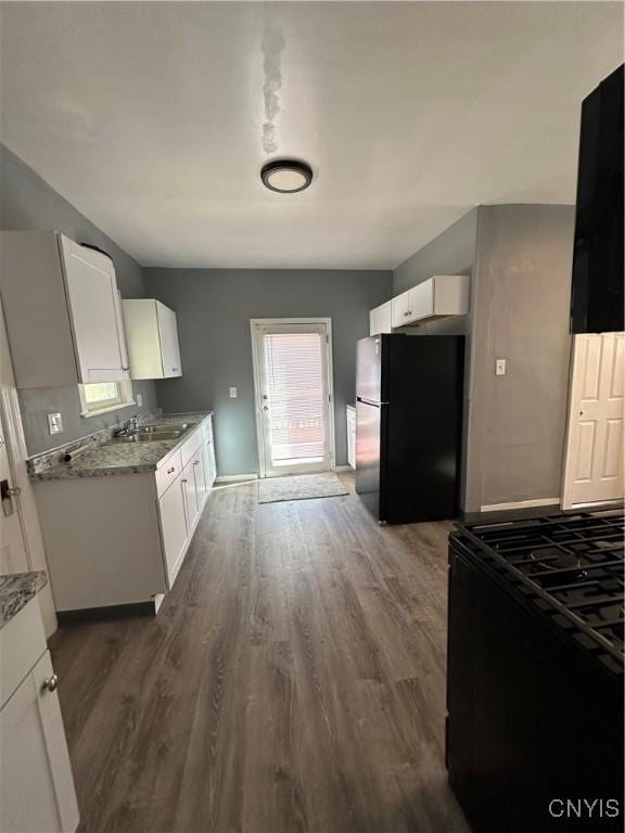 kitchen featuring freestanding refrigerator, white cabinetry, dark wood-style flooring, and gas stove