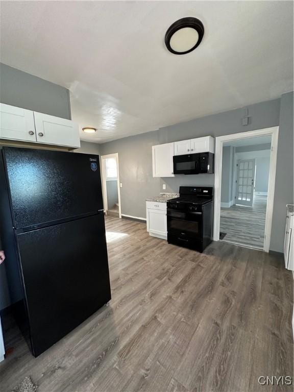 kitchen featuring white cabinetry, baseboards, black appliances, and wood finished floors