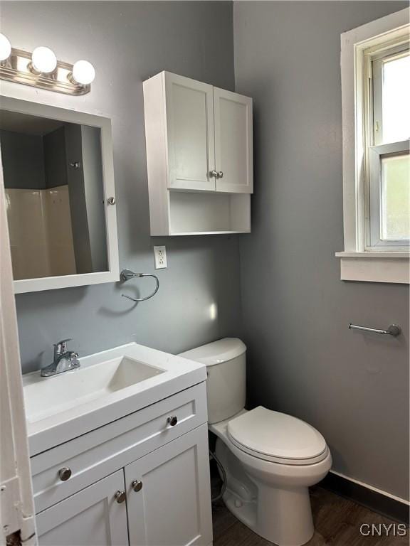 bathroom featuring toilet, baseboards, vanity, and wood finished floors