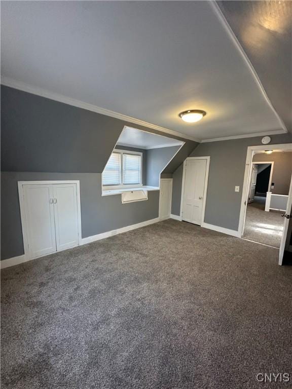 bonus room with vaulted ceiling, dark colored carpet, and baseboards