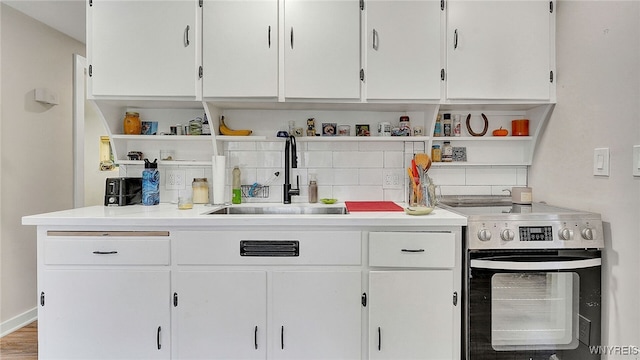 kitchen with a sink, open shelves, light countertops, and stainless steel range with electric cooktop