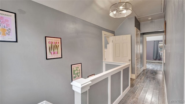 hall featuring lofted ceiling, attic access, baseboard heating, and wood finished floors