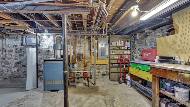 unfinished below grade area featuring electric panel, a heating unit, and a workshop area