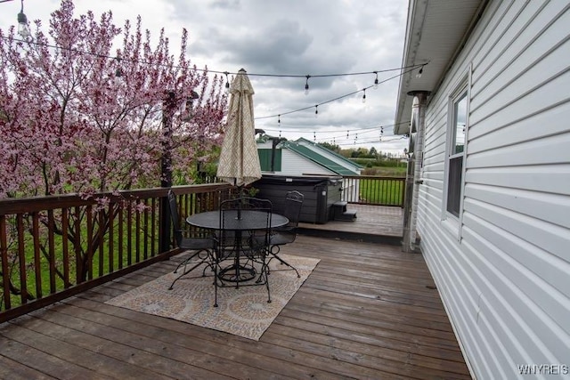 wooden deck with outdoor dining space and a hot tub