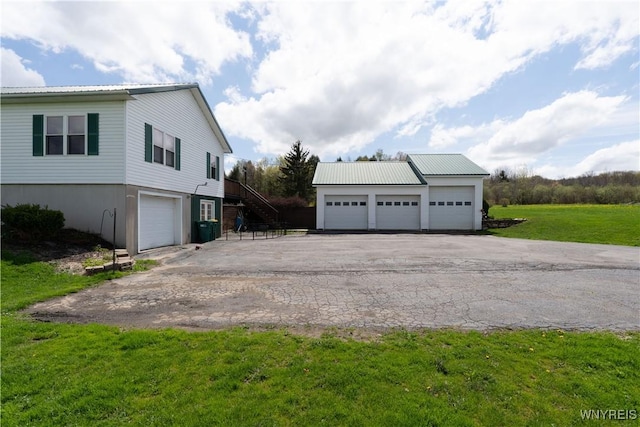 view of side of property with stairs, metal roof, a lawn, and an outdoor structure