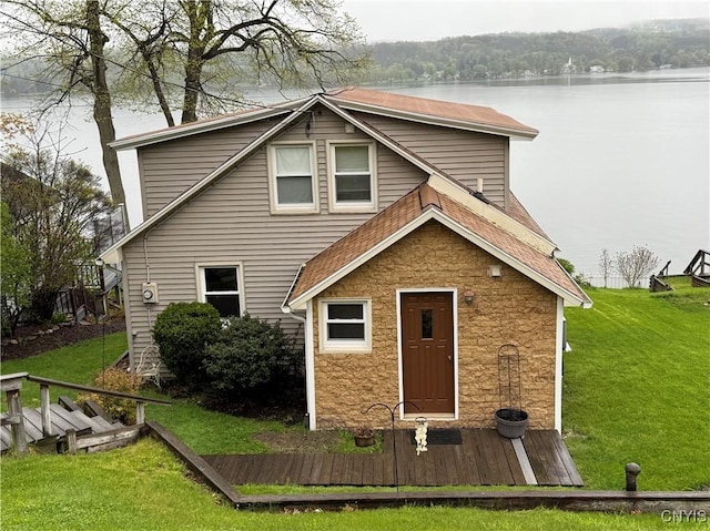 2366 Olanco Rd, Spafford, NY 13110 - rear view of property featuring stone siding, a lawn, a water view, and roof with shingles