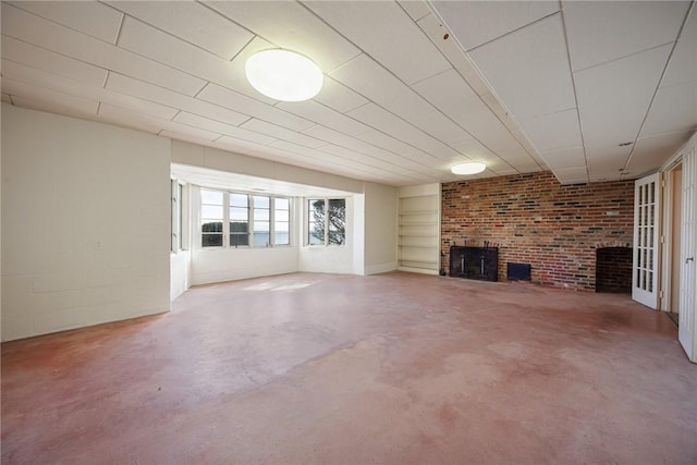 unfurnished living room with a fireplace, concrete flooring, and built in shelves