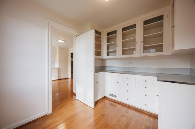 kitchen with light wood finished floors, glass insert cabinets, and white cabinets