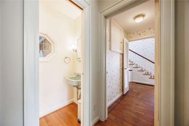 hallway with wood finished floors, baseboards, and stairway