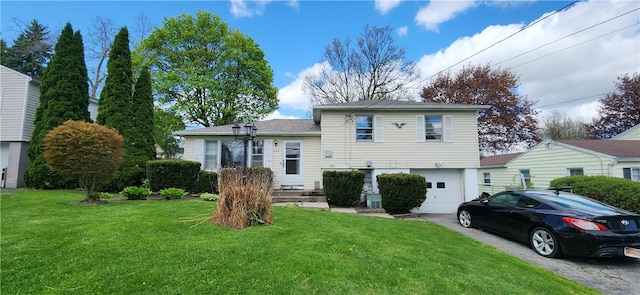 back of house featuring asphalt driveway, an attached garage, and a lawn
