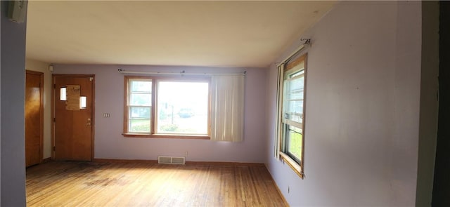 unfurnished room with healthy amount of natural light, light wood-type flooring, and baseboards