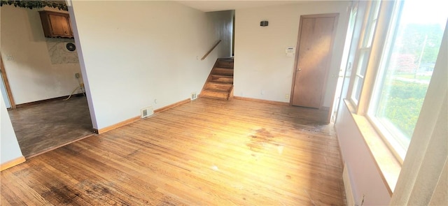 unfurnished living room featuring light wood-style floors, stairway, and baseboards