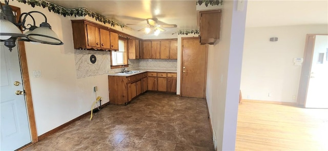 kitchen with brown cabinets, a ceiling fan, tasteful backsplash, a sink, and light countertops