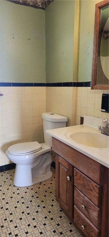 bathroom featuring tile walls, toilet, vanity, and wainscoting