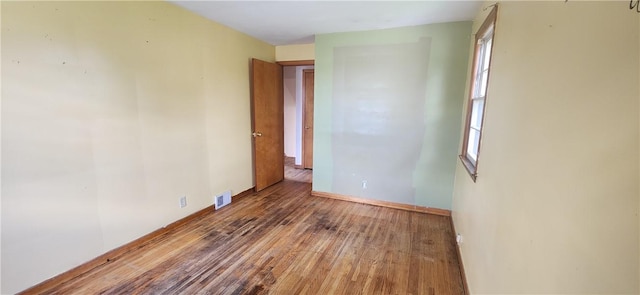 empty room featuring hardwood / wood-style floors and baseboards