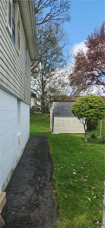 view of green lawn featuring an outdoor structure and a storage unit