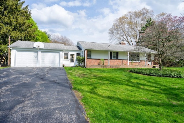 ranch-style house featuring an attached garage, a chimney, brick siding, driveway, and a front yard