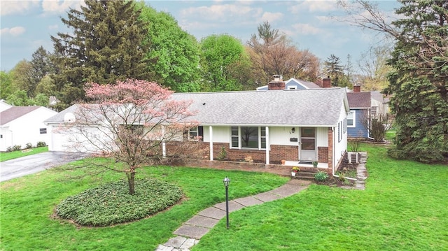 ranch-style home with brick siding, asphalt driveway, a front yard, covered porch, and a shingled roof