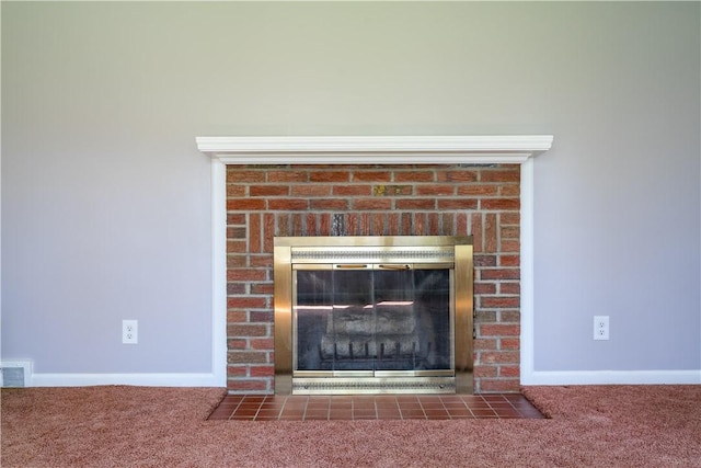detailed view of a brick fireplace, carpet, and baseboards