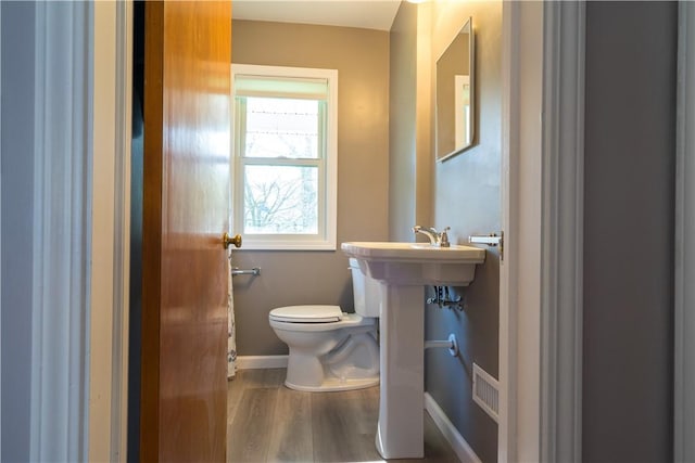 bathroom with toilet, baseboards, and wood finished floors