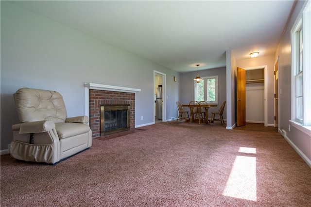 carpeted living area featuring plenty of natural light, a fireplace, and baseboards