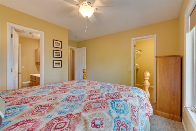 carpeted bedroom with a closet, ensuite bathroom, a spacious closet, ceiling fan, and baseboards