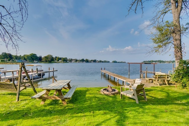dock with an outdoor fire pit, a lawn, and a water view