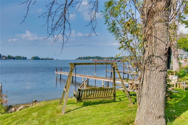 dock area with a lawn and a water view