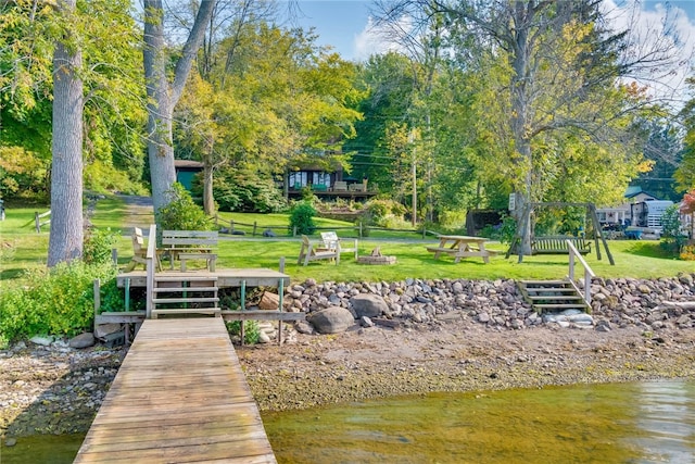 dock area featuring a lawn and view of wooded area