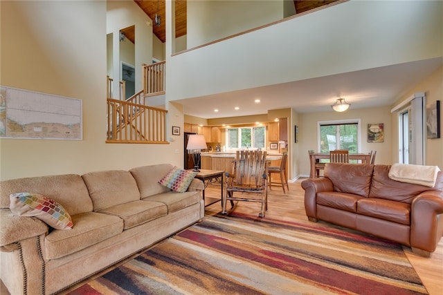 living room with light wood-style flooring, recessed lighting, stairway, and a high ceiling