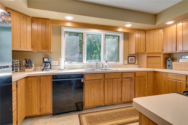 kitchen with black dishwasher, a sink, recessed lighting, light countertops, and freestanding refrigerator