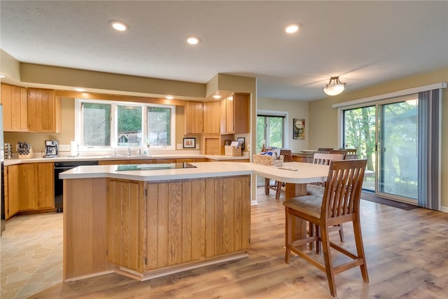 kitchen with dishwasher, light countertops, stovetop, a kitchen island, and recessed lighting