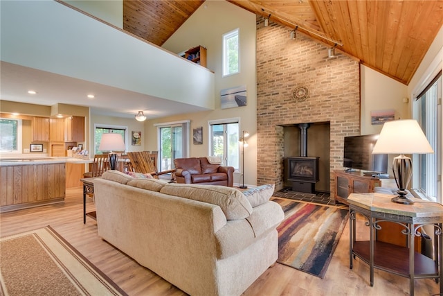 living area with plenty of natural light, light wood-style flooring, wood ceiling, high vaulted ceiling, and a wood stove