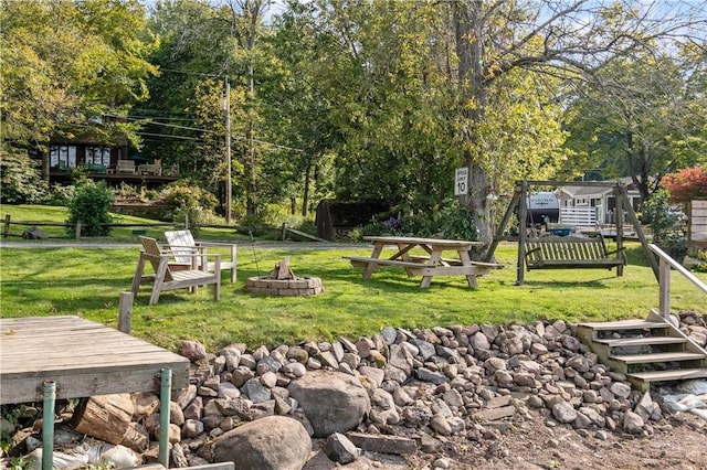 view of community with an outdoor fire pit and a yard