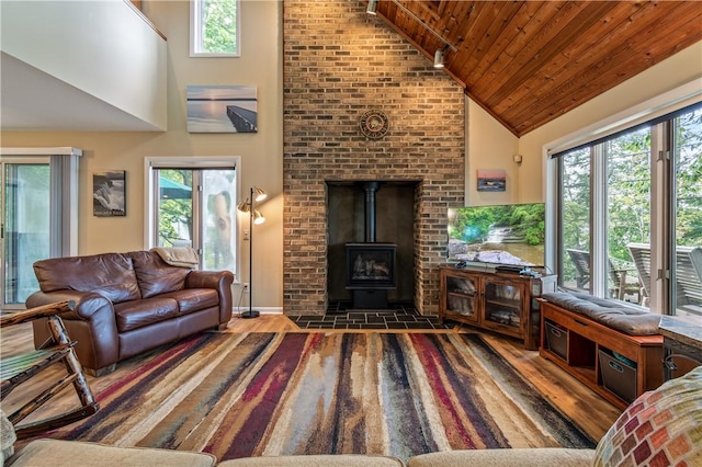 living area featuring high vaulted ceiling, a wood stove, healthy amount of natural light, wood finished floors, and wood ceiling