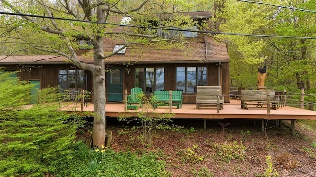 back of house with a deck and roof with shingles
