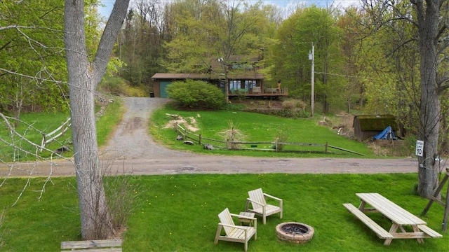 surrounding community featuring a fire pit, a yard, and a forest view