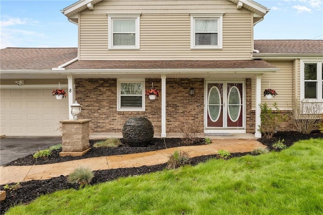 view of front of home featuring an attached garage, roof with shingles, brick siding, a porch, and driveway
