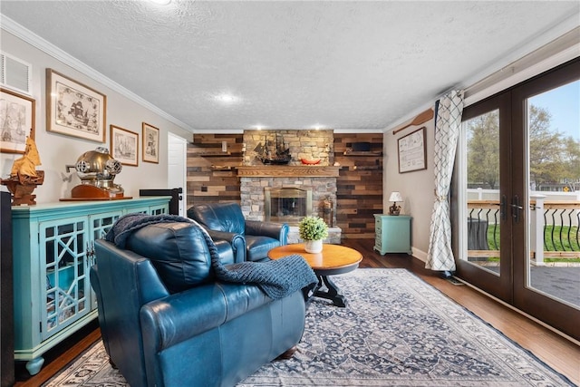 living room featuring a textured ceiling, french doors, ornamental molding, wood finished floors, and wood walls